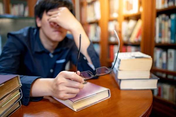 아시아인 대학생은 도서관에서 연구를 빈티지 책꽂이를 읽으면서 스트레스와 불안을 느낀다 — 스톡 사진