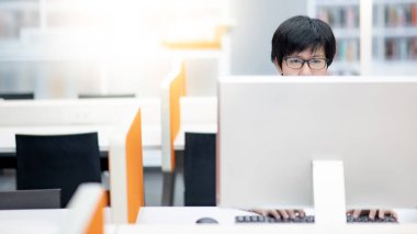 Asyalı iş adamı ofis binasında kişisel bilgisayar kullanıyor. Çevrimiçi platformda çalışan erkek çalışan. İnternet ağı ve modern teknolojiyle akıllı çalışın.