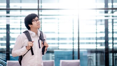 Halka açık alanda çanta taşıyan kendine güvenen Asyalı adam. Hedef kavramına ulaş