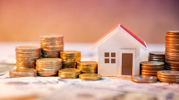 Real estate or property investment. Home mortgage loan rate. Saving money for retirement concept. Coin stack on international banknotes with house model on table. Business growth background