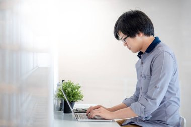 Asyalı iş adamı gözlük takıyor. Ev işleri ofisinde çalışan dizüstü bilgisayarını kullanıyor. Online konferans için yazılım kullanıyor. İş stratejisi teknolojisi. Ev kavramından çalış