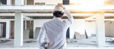 Asyalı inşaat mühendisi ya da koruma kaskı takan inşaat işçisi elinde yuvarlanmış planlar tutuyor. İnşaat alanında çalışan erkek mimar. İnşaat ve mimari tasarım kavramları