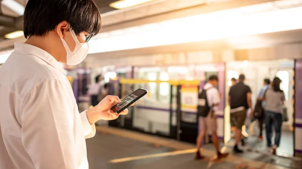 Asiatisk Mand Iført Kirurgisk Ansigtsmaske Ved Hjælp Smartphone Skytrain Station - Stock-foto