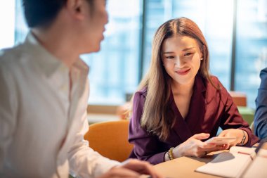 İş toplantısı ve ortaklık konsepti. Çekici Asyalı iş kadını iş yerindeki proje hakkında iş arkadaşlarıyla konuşuyor. İş arkadaşları konferans odasında fikir alışverişinde bulunuyor..