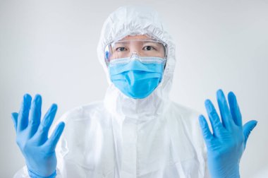 Doktor ya da doktor hastane kliniğinde steril lastik eldiven gösteriyor. Koronavirüsü (COVID-19) enfeksiyonunu önlemek için PPE giysisi, maskesi ve gözlüğü olan bir tıp çalışanı.