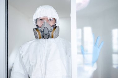 Bilimadamı ya da Virolojist adam biyolojik tehlike kimyasalı koruyucu kıyafet, gözlük ve maske takıyor. Koronavirüs (COVID-19) enfeksiyonunu önlemek için PPE ve kauçuk eldiven giyen erkek doktor veya sağlık görevlisi.