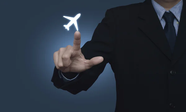 Businessman pressing airplane icon on blue background — Stock fotografie
