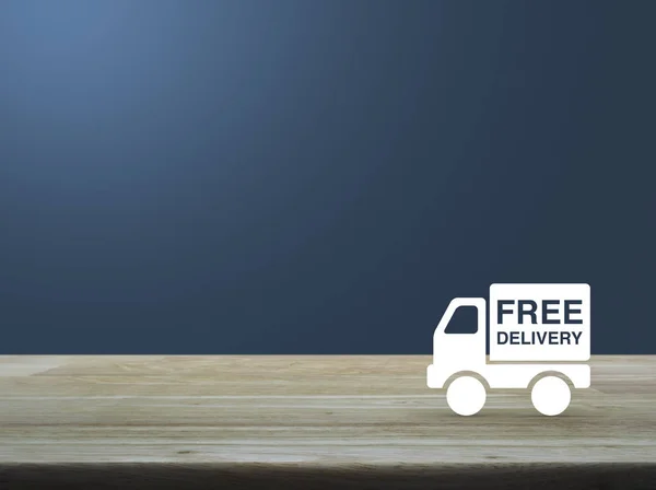 Consegna gratuita icona camion su tavolo di legno su sfondo blu — Foto Stock