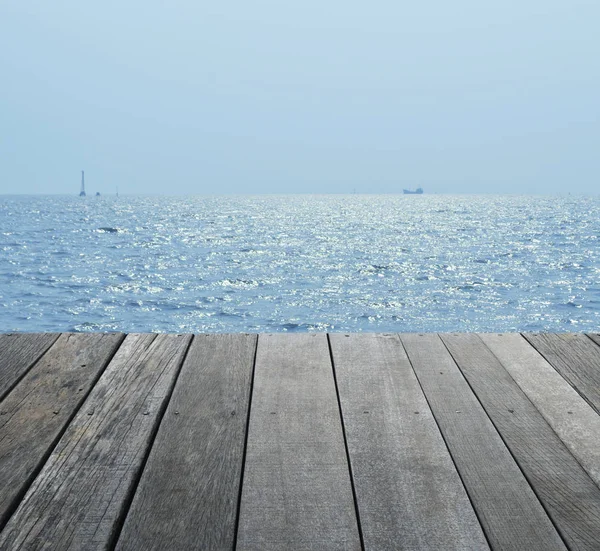 Lege oude houten vloer over boot silhouet met zee en de blauwe hemel — Stockfoto