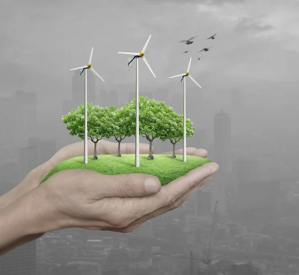 Wind turbines, grass and trees in human hands over pollution cit — Stock Photo, Image