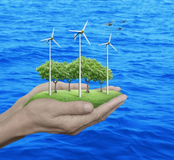 Wind turbines, grass and trees in human hands over sea — Stock Photo, Image