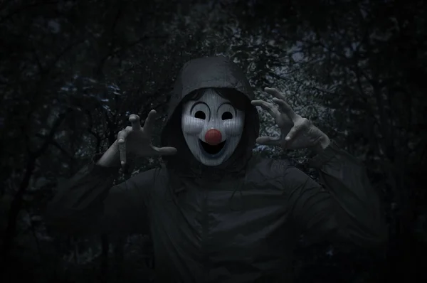 Страшный злой клоун носит куртку над жутким деревом и лесом в ночное время — стоковое фото