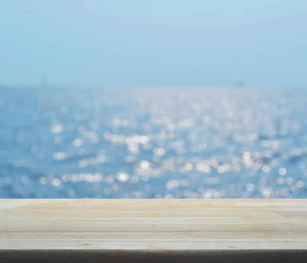 Lege houten tafel met vervaging blauwe zee golven met bokeh licht — Stockfoto