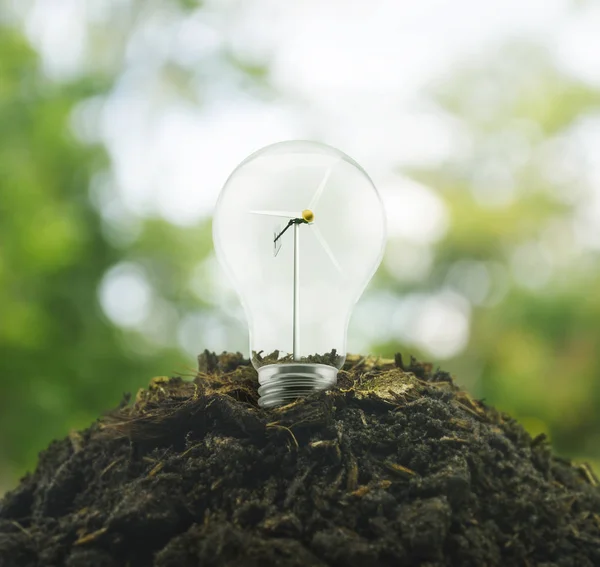 Light bulb with wind turbine inside on pile of soil over green e — Stock Photo, Image