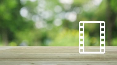 Parktaki bulanık yeşil ağacın üzerinde film yassı ikonu olan oyun düğmesi, iş sineması çevrimiçi kavramı
