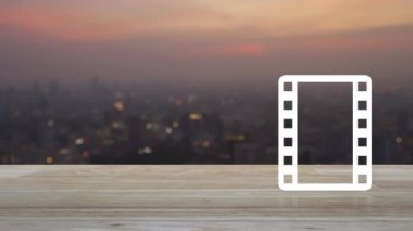Sıcak gün batımında şehir manzarası bulanıklığı üzerine ahşap masa üzerinde film yassı ikonu ile oynat, iş sineması çevrimiçi konsepti