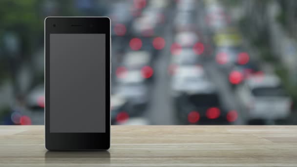地图定位按钮在现代智能手机屏幕上的木制桌子上 交通高峰时间与汽车和道路的模糊 地图指针在线导航的概念 — 图库视频影像