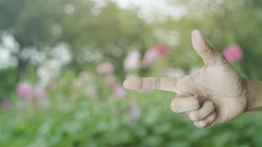 CCTV kamera düz simgesi parktaki bulanık pembe çiçek ve ağaç üzerinde parmak üzerine parmak, iş güvenliği ve güvenlik konsepti