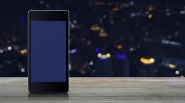 Modem akıllı cep telefonu ekranında, renkli gece lambası şehir kulesi ve gökdelen, iş güvenliği ve güvenlik online konsepti üzerinde, kapalı ahşap masadaki mobese üzerine kapalı kamera yassı simgesi