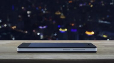 Motosiklet düz simgesi, modern akıllı cep telefonu ekranında ahşap masa üzerinde bulanık gece lambası şehir kulesi ve gökdelen, iş teslimatı online konsepti