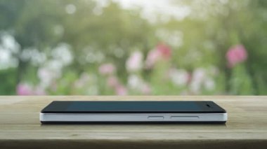 Ücretsiz dağıtım kamyonu düz simgesi modern akıllı cep telefonu ekranı ahşap masa üzerinde bulanık pembe çiçek ve ağaç parkta, iş ulaşımı online konsept