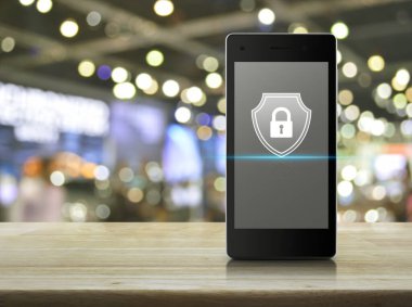 Modern akıllı cep telefonu ekranında asma kilit bulanık ışıkta ahşap masada ve alışveriş merkezinin gölgesinde iş güvenliği online konsepti