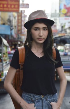 Sırtında sırt çantası ve şapkasıyla genç Asyalı bir gezgin Çin kasabasının, Bangkok 'un, Tayland' ın, seyahat tatil rahatlama konseptinin başında duruyor.