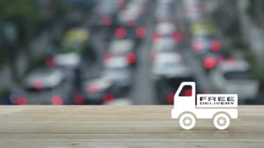 Ücretsiz teslimat kamyonu düz simgesi ahşap masa üzerinde kalabalık saatte arabalar ve yol, iş ulaşımı konsepti