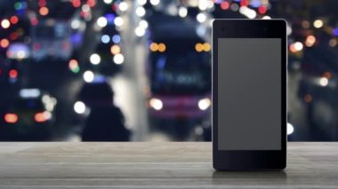 Taksinin düz simgesi, modern akıllı cep telefonu ekranında, ahşap masanın üzerinde, gece yarısı renkli trafik sıkışıklığı caddesinde, arabalarla, iş ulaşımı online servis konseptiyle.