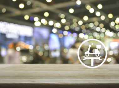 Motosikleti tamir ederken, tahta masanın üzerinde ingiliz anahtarı düz simgesi, bulanık ışık ve alışveriş merkezinin gölgesi, iş tamiratı motosiklet servisi konsepti.