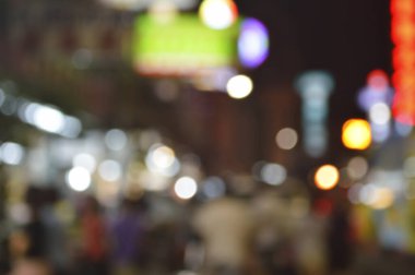 Renkli gece lambası kulesinde yürüyen kalabalığın soyut bulanık görüntüsü.