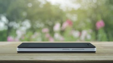Modern akıllı cep telefonu ekranındaki yassı simge parktaki bulanık pembe çiçek ve ağacın üzerindeki ahşap masa üzerinde iş hukuku hizmeti online konsepti