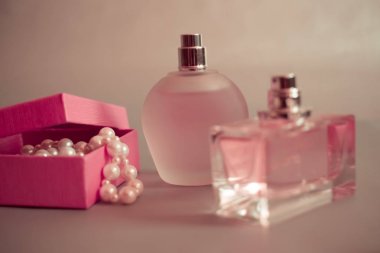 Parfüm şişeleri ve gri arka plan üzerinde inci boncuklar ile pembe kutu