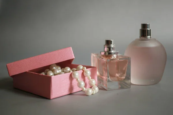 Butelek perfum i różowe pudełko z perła koraliki na szarym tle — Zdjęcie stockowe