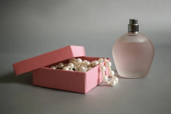 Flacon de parfum et boîte rose avec perles de perles sur fond gris — Photo