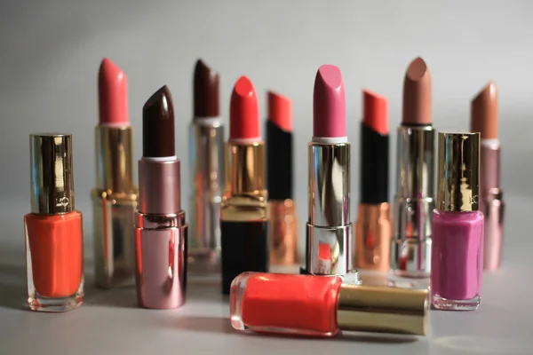 Set aus bunten Lippenstiften und Nagellacken auf grauem Hintergrund — Stockfoto