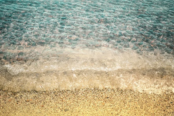 Sandy beach a průsvitného moře-vlny, oblázky pod vodou — Stock fotografie