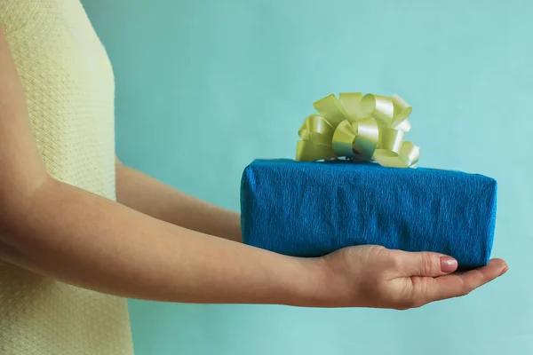 Caixa de presente nas mãos da mulher, dar e receber um presente, amarelo e azul — Fotografia de Stock