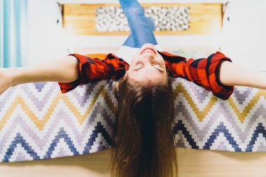 Genç ve güzel bir kadın kanepede sırtüstü uzanıyor ve rahatlama anının tadını çıkarıyor.