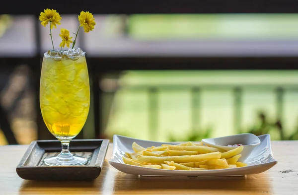 Chrysanthemum tea with ice in glass and french fries — Stock Photo, Image