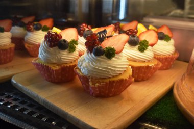 Ahşap arka planda çilekli ve ahudududulu kekler.