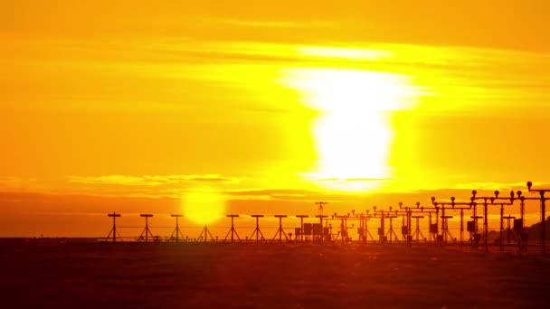 Aviones aterrizando en un día nublado de atardecer mientras las luces se encienden en el aeropuerto — Vídeo de stock