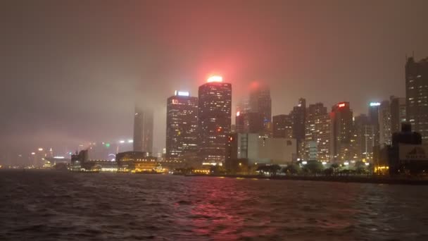 Hong kong - März 2016: Bootsfahrt mit nächtlichem Blick auf Hochhäuser entlang der Küste an einem nebligen Abend — Stockvideo