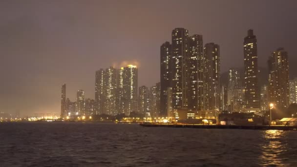 霧の夜の海岸沿いの高層ビルの夜景とボートに乗る — ストック動画