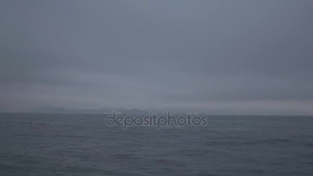 Paseo en barco en el océano en un día nublado tormentoso con la isla en el fondo en una noche brumosa — Vídeos de Stock