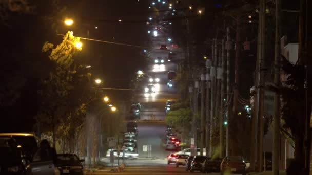 Voiture descendant sur une colline escarpée la nuit avec la circulation passant au premier plan — Video