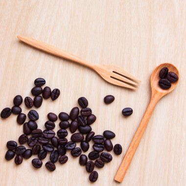 coffee beans, spoon, wooden scoop and wood board with a cup of tea on a background