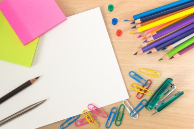 office supplies and blank sheet on wood table.