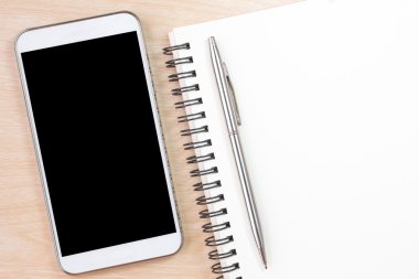 top view of notepad with blank screen and mobile phone on wooden table