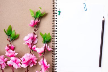 pink pencil and pen with a book on a white background